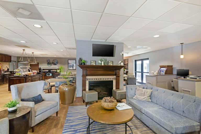 Spacious hotel lobby lounge with fireplace, gray sofas, wood furnishings, and contemporary design