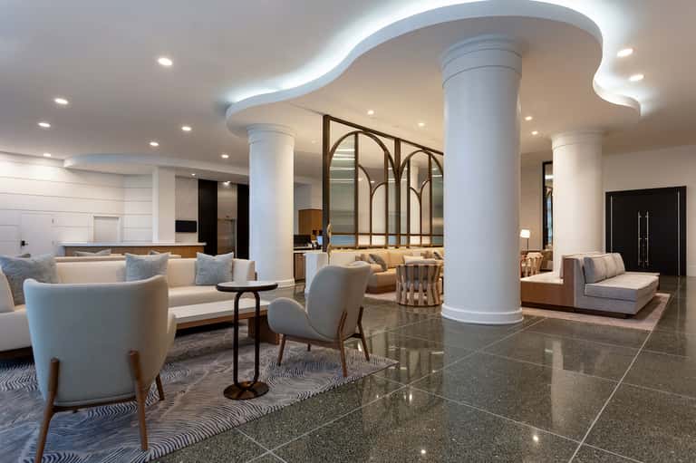 Modern hotel lobby with curved ceiling, white columns, and contemporary seating