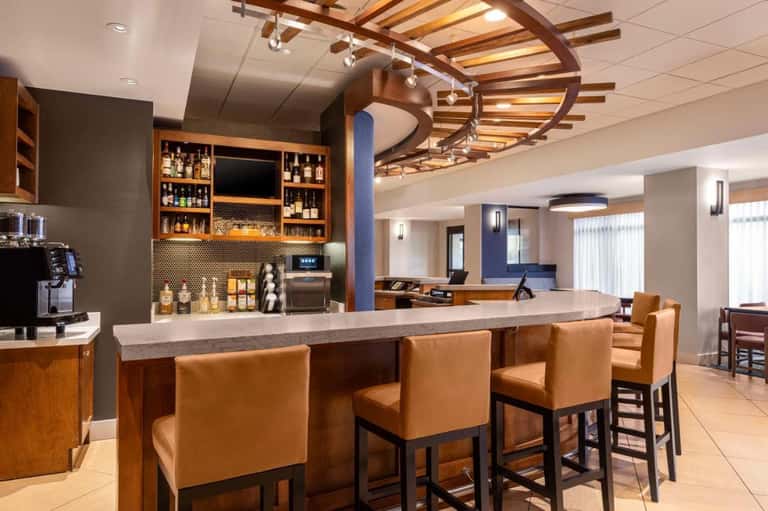 Modern hotel bar with wooden ceiling beams, leather seating, and well-stocked liquor shelves