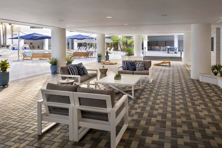 Covered patio area with comfortable seating, blue umbrellas, and ocean views