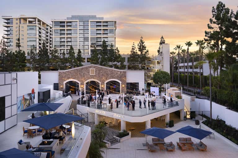 Urban resort courtyard with arched brick structure, gathering spaces, and surrounding buildings