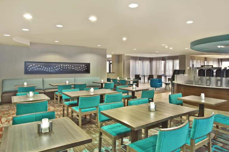 Elegant hotel restaurant with turquoise seating, natural lighting, and curved architectural details