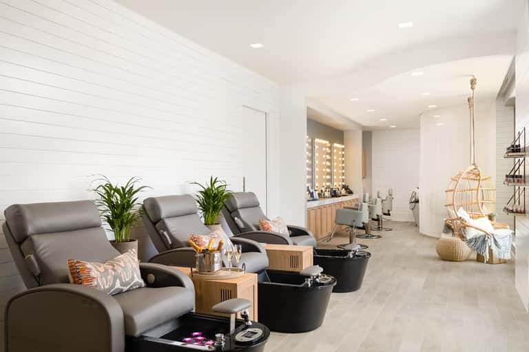 Luxury spa treatment room with massage chairs, mirrors with lighting, and modern wellness decor