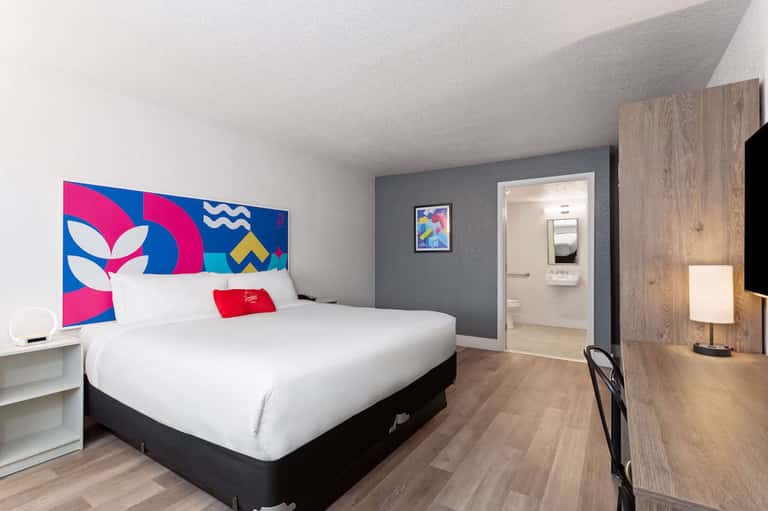 Contemporary hotel bedroom with colorful headboard art and modern furnishings