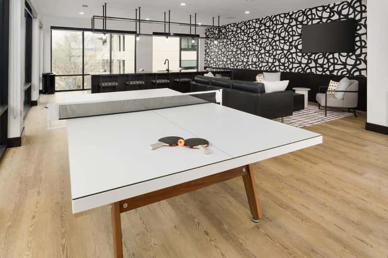 Modern recreation room with ping pong table, black sofa, fireplace, and decorative wall paneling