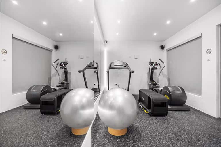 Modern fitness center with treadmills, exercise bikes, and stability balls on gray flooring
