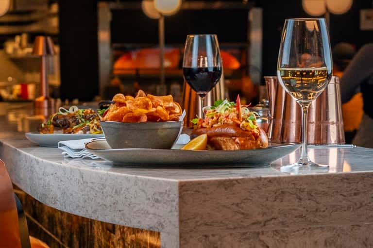 Fine dining table with wine glasses, fried food, and ocean view backdrop