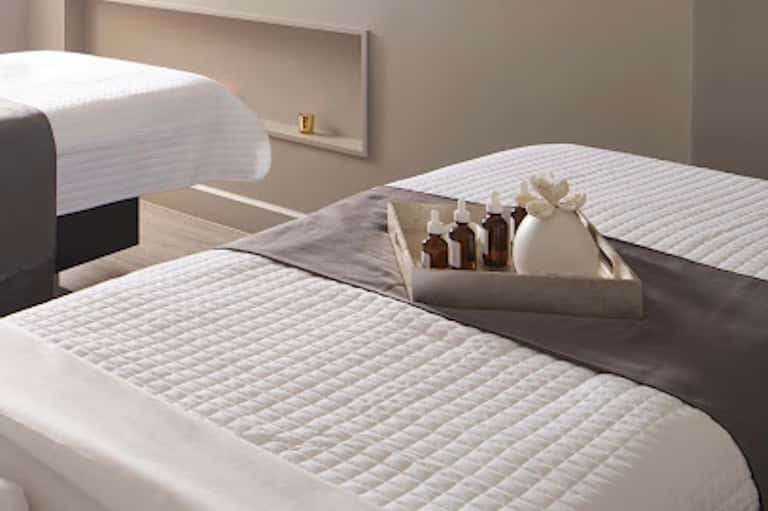 Minimalist spa treatment beds with white linens and amenity bottles