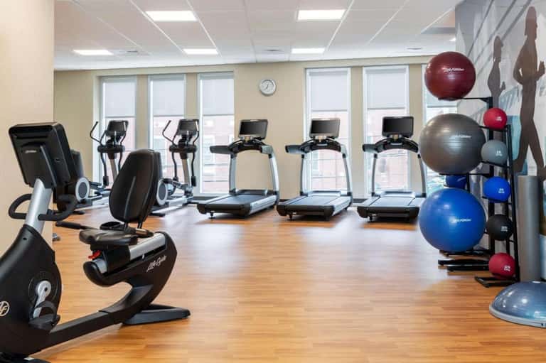 Modern fitness center with treadmills, stationary bikes, exercise balls, bright windows