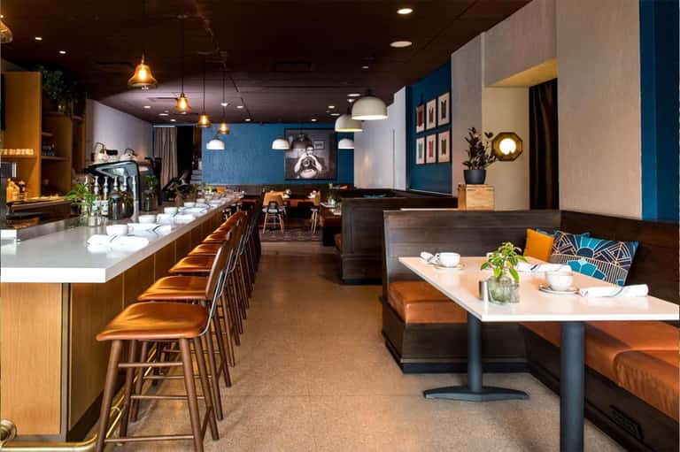 Modern hotel restaurant and bar with blue accent walls, wood furnishings, and ambient lighting