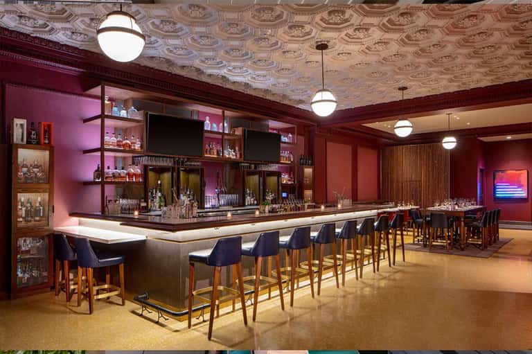 Upscale bar lounge with burgundy walls, elegant bar seating, and decorative shelving