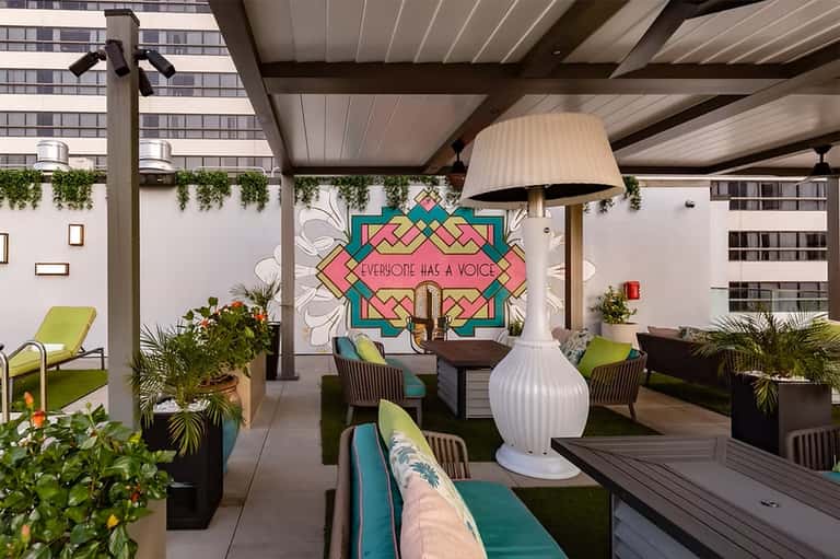 Modern rooftop lounge with colorful geometric wall art, contemporary furniture, and hanging pendant lights