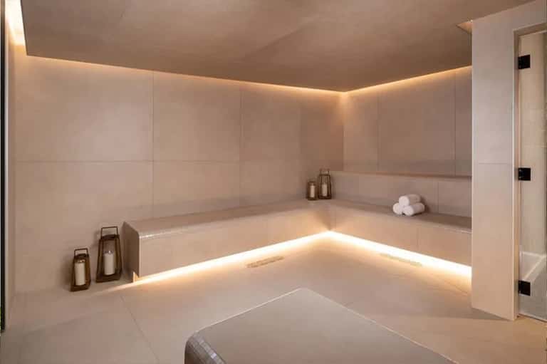 Luxurious spa bathroom with sunken soaking tub, ambient lighting, cream tiles, and minimalist design