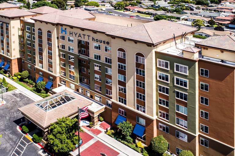 Aerial view of Hyatt House multi-story hotel building with tan and brown exterior and copper roof