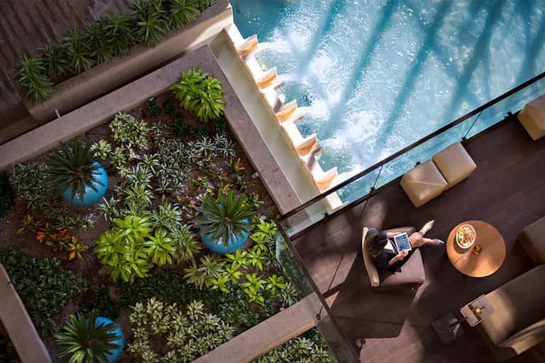 Aerial view of pool with lounge chairs and guest relaxing on terrace with garden landscaping