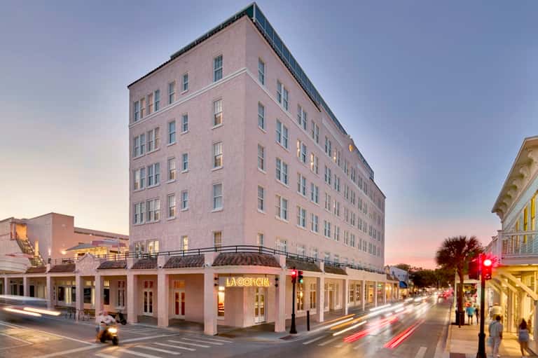 Historic hotel building exterior at dusk with ground-floor retail, classical architecture, and street-level storefronts