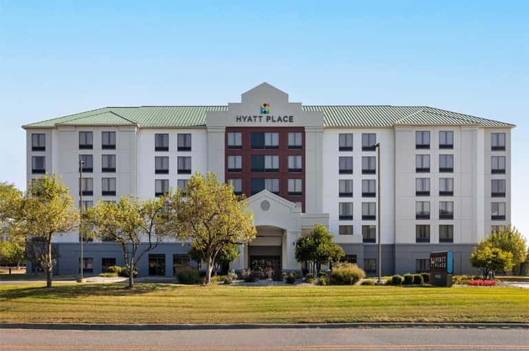 Hyatt Place hotel exterior with white facade, red center section, and landscaped grounds
