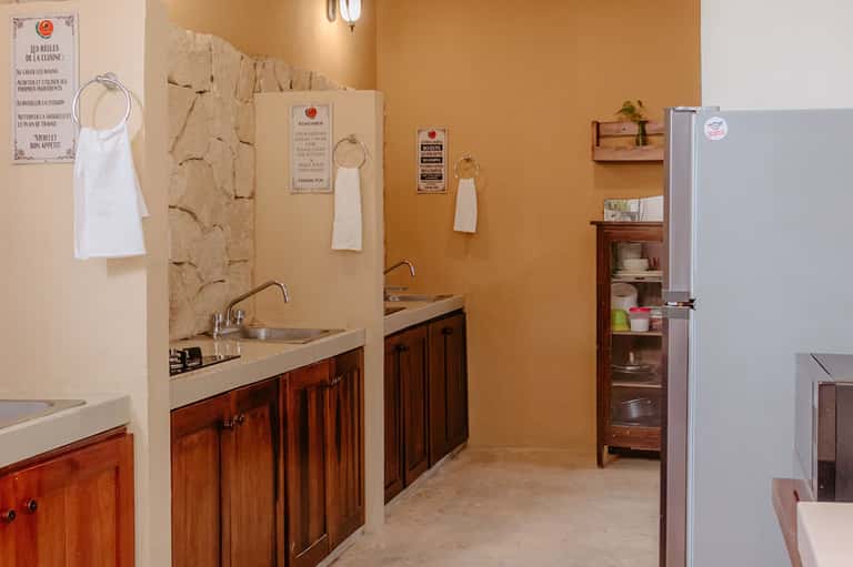 Kitchen prep area with wooden cabinetry, dual sinks, and French culinary instruction posters