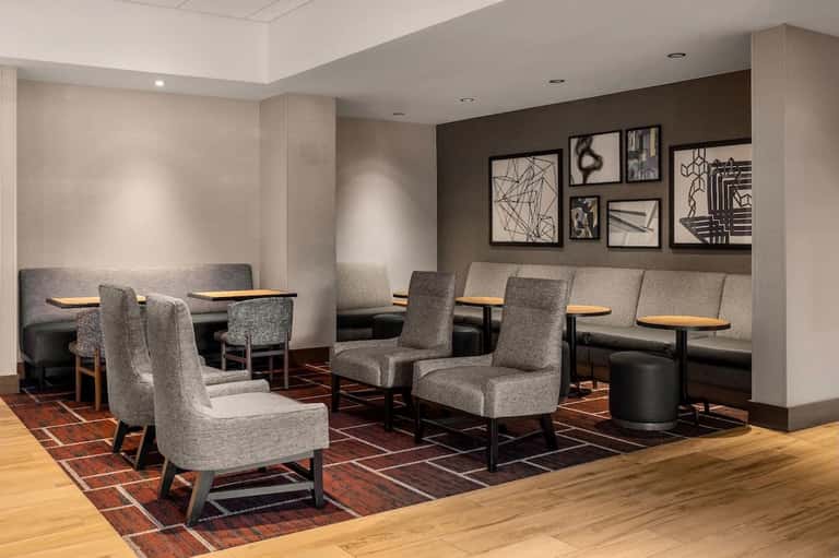 Hotel lounge with gray upholstered chairs, low tables, and contemporary wall art