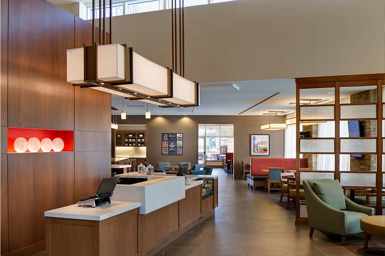 Modern hotel lobby with wood accents, reception desk, contemporary furniture, and open layout design