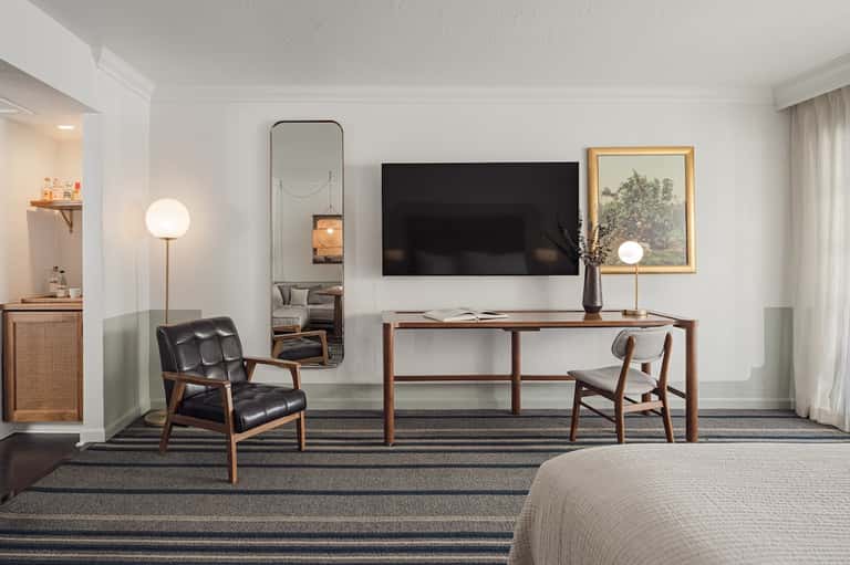 Upscale hotel room with desk, chair, TV, and mid-century modern furnishings