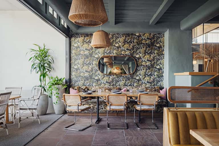 Modern dining area with patterned wallpaper, woven pendant lights, and wooden chairs