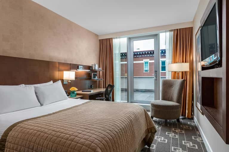 Contemporary hotel bedroom with brown bedding, terrace view, and flat-screen TV