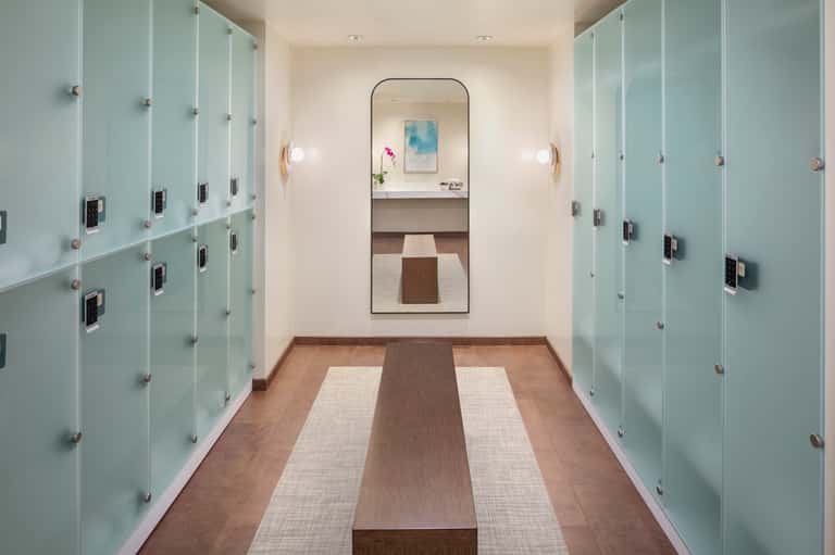 Hotel changing room corridor with frosted glass lockers and mirrored vanity