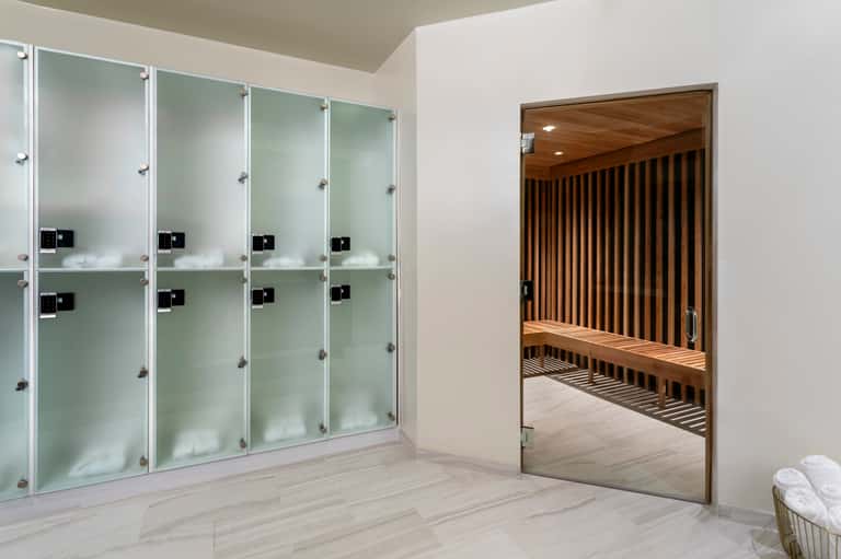 Modern spa locker room with glass lockers and wooden sauna room entrance