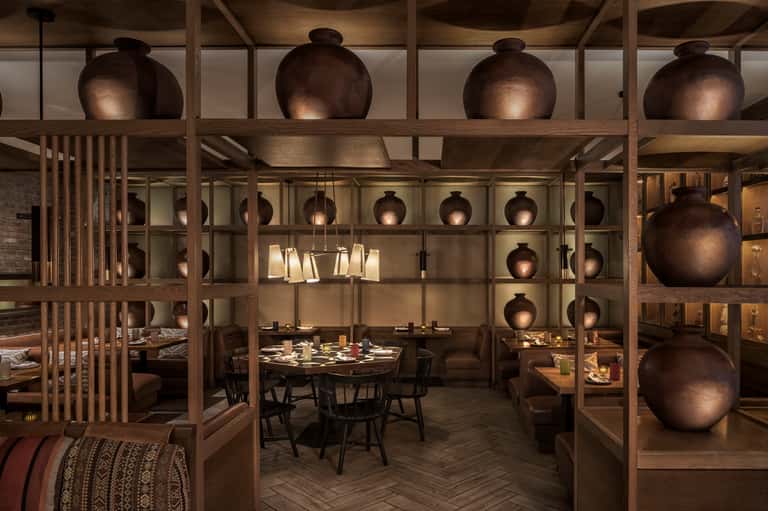 Modern restaurant interior with wooden shelving, large bronze decorative spheres, and dining tables