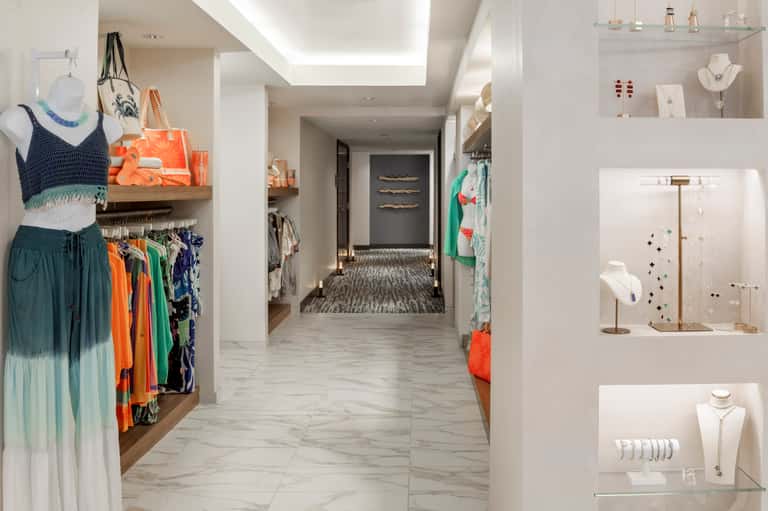 Modern retail corridor with clothing displays, jewelry cases, and colorful merchandise on shelves