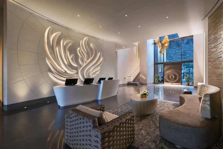 Modern hotel lobby with illuminated flame sculpture, reception desk, and floor-to-ceiling windows