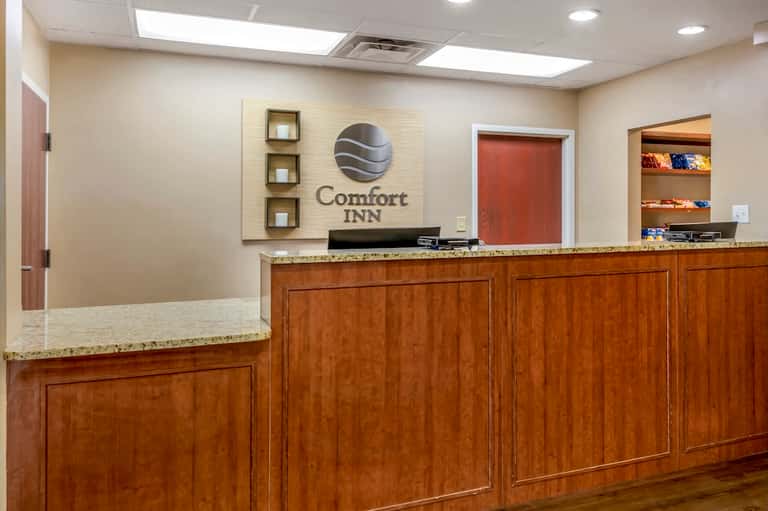 Comfort Inn front desk with wooden cabinetry, logo signage, and warm interior lighting