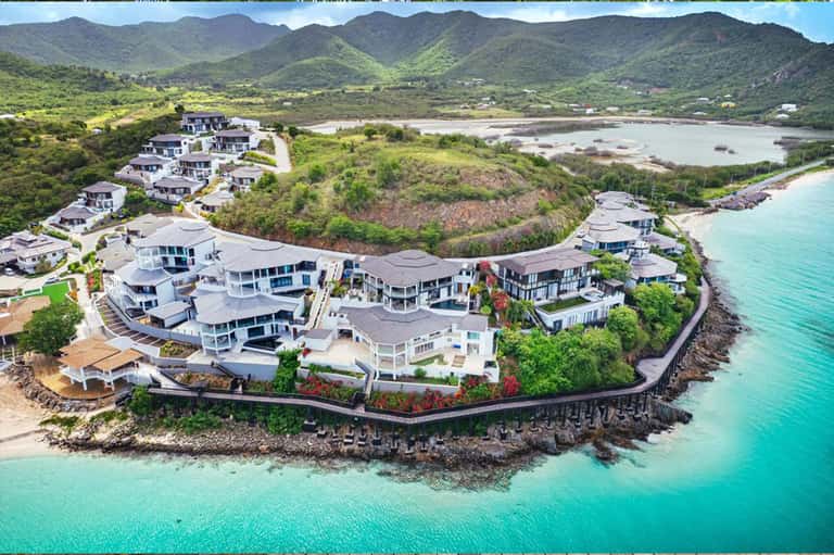 Aerial view of luxury beachfront resort with white modern villas on turquoise ocean cove
