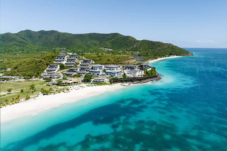 Aerial view of luxury beach resort with white villas on turquoise waters and sandy beach