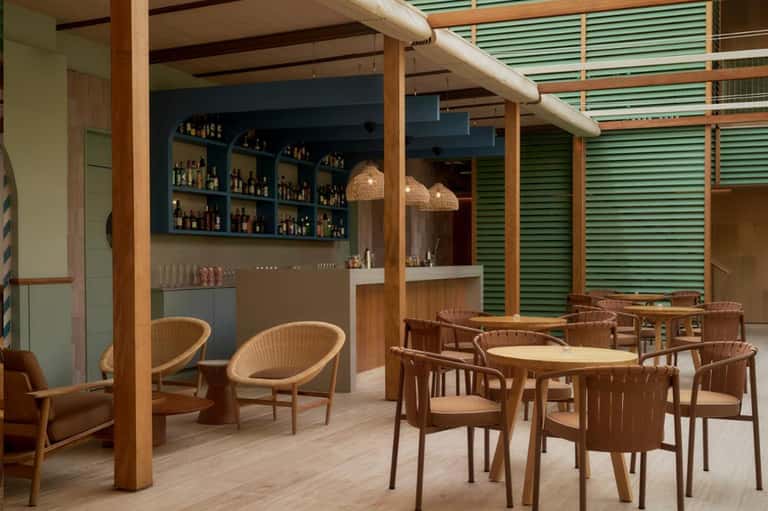Contemporary restaurant lounge with wooden beams, turquoise shutters, and casual seating areas