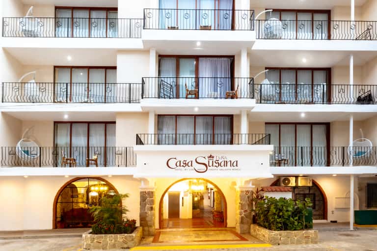Mediterranean-style white building with multiple balconies and arched ground-floor entryway at dusk