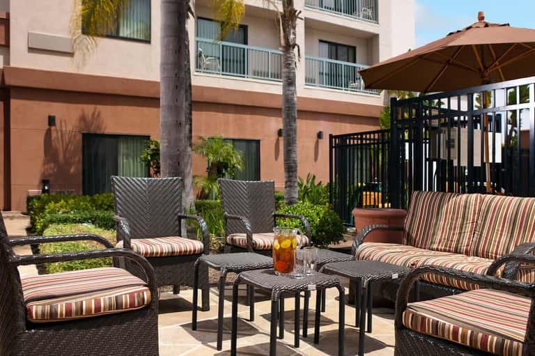 Outdoor courtyard seating area with striped cushioned furniture and large brown umbrella