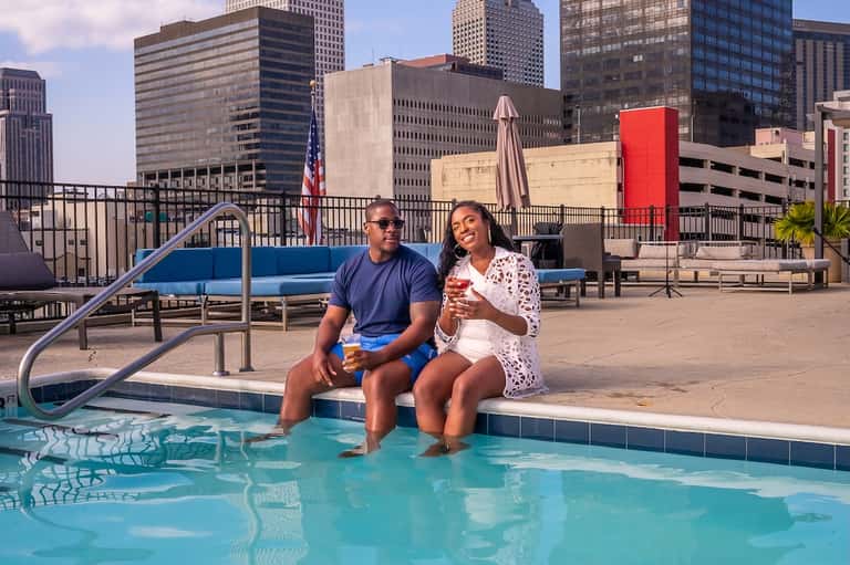 Couple relaxing by rooftop pool with downtown skyline views and summer beverages