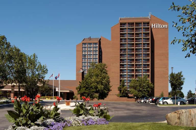 Hilton hotel exterior with brick facade, manicured landscaping, and red flowers