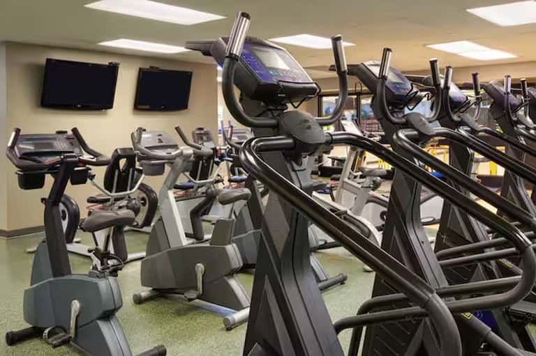 Modern fitness center with stationary bikes, ellipticals, and wall-mounted monitors