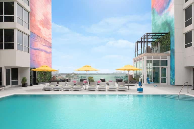 Modern pool deck with yellow umbrellas, lounge chairs, and colorful building architecture