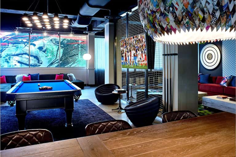 Game room with pool table, lounge seating, TV screens, and colorful accent lighting