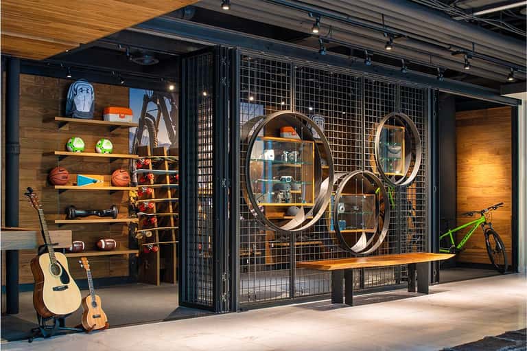 Modern sports lounge with guitars, bicycles, and circular mirrors on display shelving