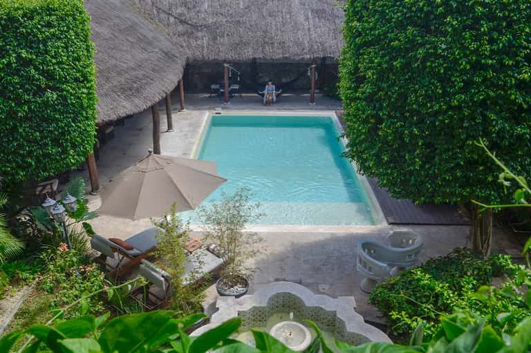 Overhead view of rectangular pool surrounded by lush green vegetation and lounge chairs