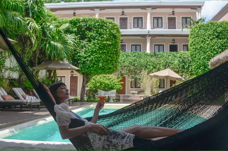 Woman relaxing in hammock by tropical pool with ivy-covered courtyard