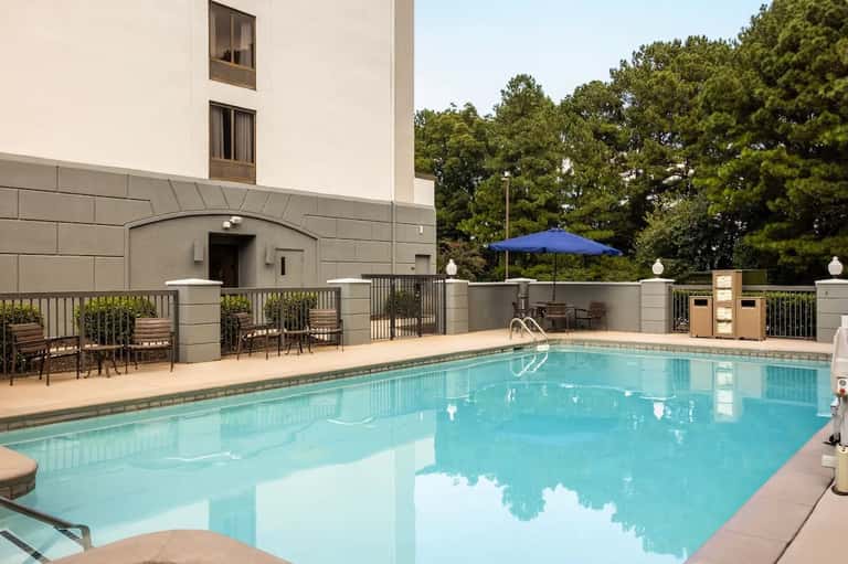 Indoor swimming pool with blue umbrella, lounge chairs, and building exterior view