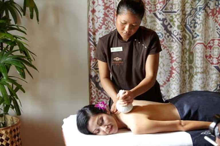 Spa therapist providing shoulder massage to relaxed client on treatment table