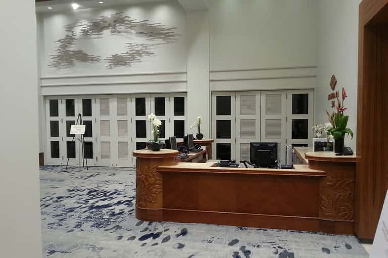 Bright lobby area with wooden reception desk, white doors, and decorative artwork