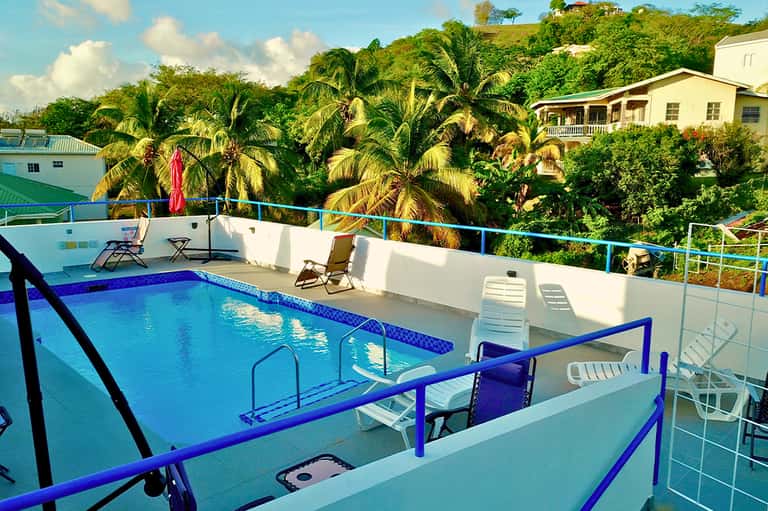 Rooftop swimming pool with vibrant blue water overlooking tropical hillside community